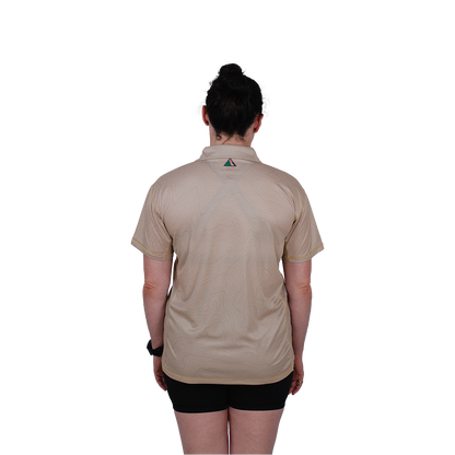 Person wearing a beige shirt with a logo on the back, standing against a white background