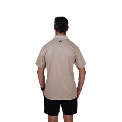 Man wearing a beige trail running shirt with a logo on the back against a white background